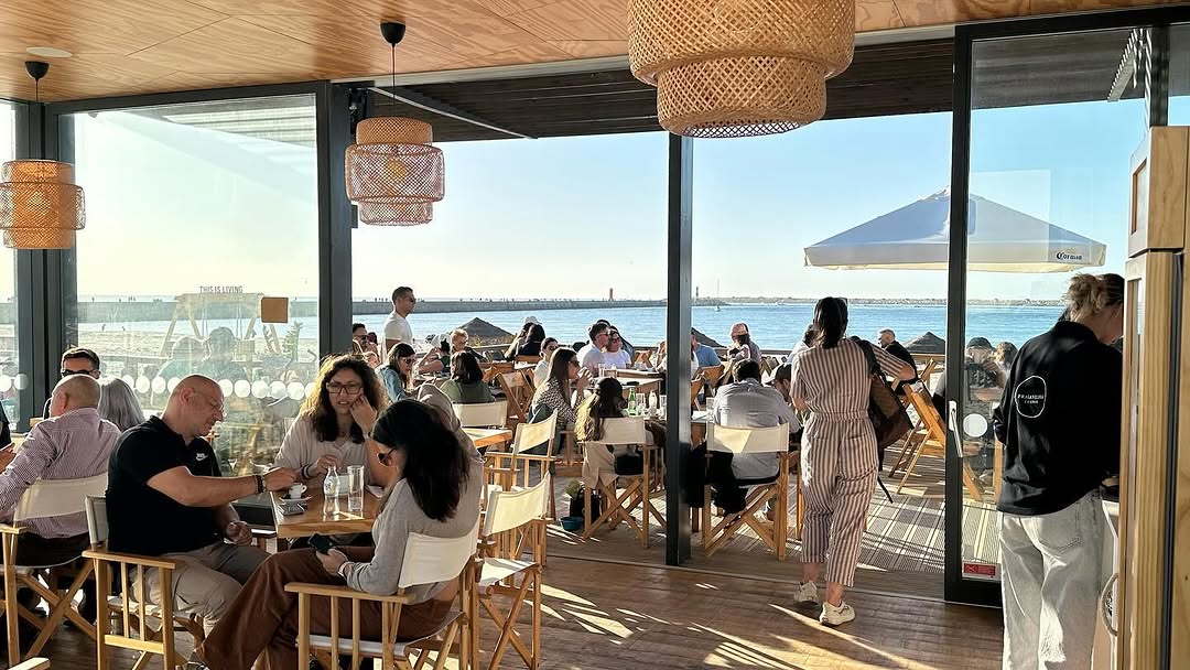 Interior do Praia Velha Lounge cheio com vista mar